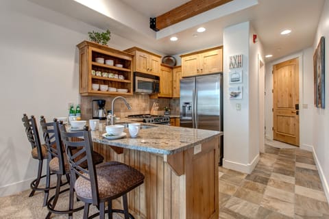 Fully Equipped Kitchen with stone countertops, stainless steel appliances, ice maker, and bar seating for three