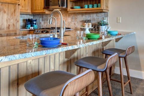 Fully Equipped Kitchen with stone countertops, stainless steel appliances, ice maker, and bar seating for three