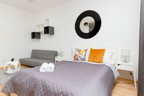 A bedroom ara featuring a gray bed, white linens, and a bright yellow accent pillow for a cheerful look.