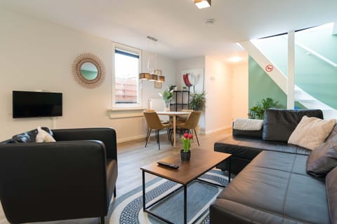 Bright and spacious living area with modern decor, comfortable seating, and dining table – ideal for relaxing after a day in Alkmaar.