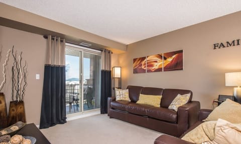 Living room with a Smart TV, cozy couches and walkout access to the balcony.