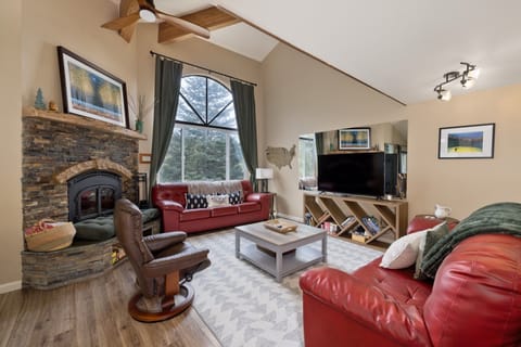 Gather in your spacious living room with soaring vaulted ceilings, a cozy stone fireplace, and comfortable leather seating. Natural light floods through tall windows while modern amenities complete your mountain retreat.