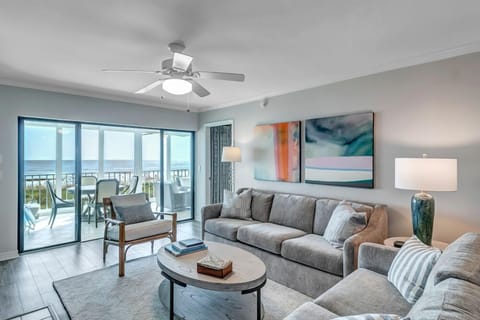 - Spacious main living area with plush sectional, sleek decor, and balcony views
- Ceiling fan, soft lighting, and modern art make the space feel light and inviting
- Unwind indoors while enjoying views of sand dunes and sparkling water