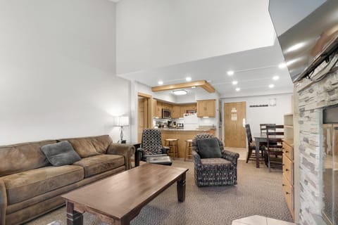 Settle into your spacious living area where warm wood accents and cozy furnishings create the perfect retreat. You'll love gathering around the coffee table or preparing meals in your fully equipped kitchen.