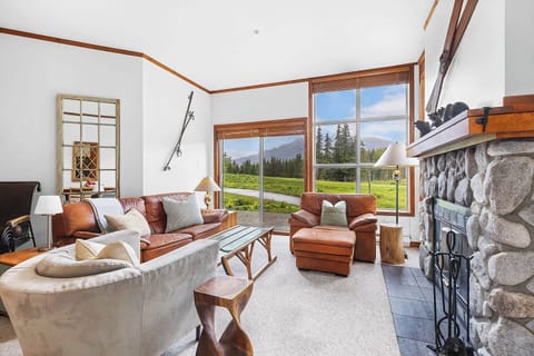 - Bright mountain-view living room with cozy stone fireplace  
- Warm tones, large windows, and plush seating for relaxation  
- Ideal space for gathering after skiing or summer adventures  

