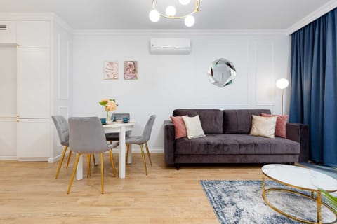 A stylish living room with a navy blue sofa, decorative cushions, and a coffee table, illuminated by natural light.
