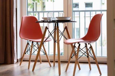A dining area with a round table and red chairs, creating a vibrant and welcoming atmosphere.
