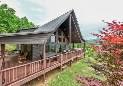 Elevated exterior view of A Walk in the Clouds featuring a covered wraparound deck and mountain setting in Bryson City. Located near Great Smoky Mountains National Park and area attractions.