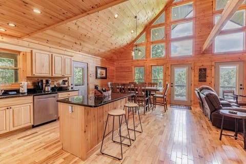 Open kitchen and dining space with vaulted ceilings and large windows filling the room with natural light.