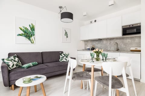 A sleek, open-plan kitchen adjacent to a dining table elegantly set with glassware and greenery.