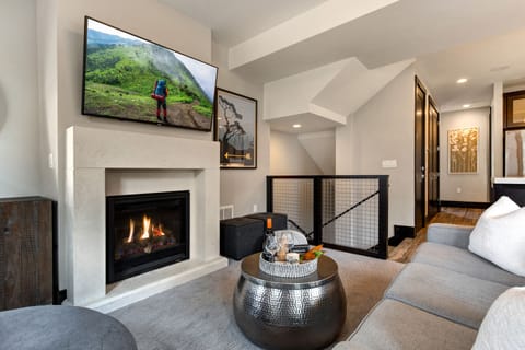 Living Room with plush contemporary furnishings including sofa bed, 55" TV, gas fireplace, and private balcony access