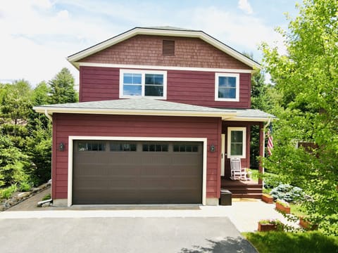 Two car garage, three floors, small porch, and rear patio with a hot tub.