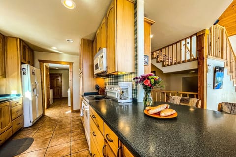 View from the end of the kitchen looking on to the upper and lower level staircase. Eat in bar & dining area open to the family room & massive views!