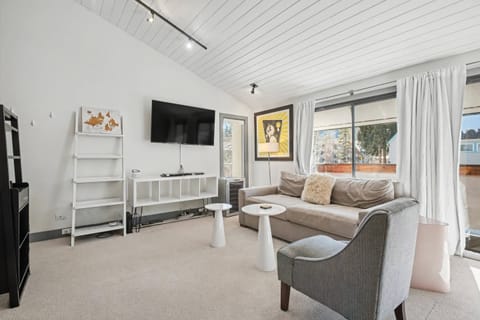 A large flat screen TV and pull out sofa bed are found in this bright and inviting living area.