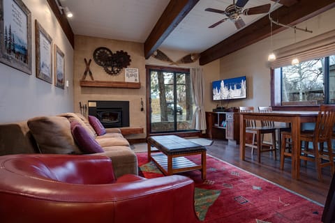 Relax in your cozy living space with exposed beams, fireplace warmth, and mountain charm after exploring the slopes.