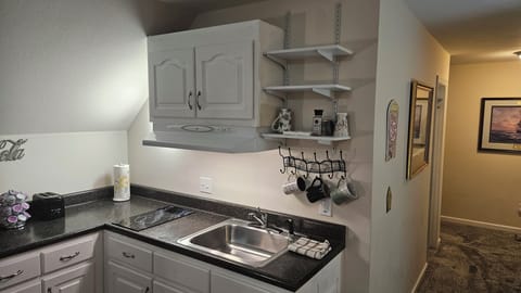 Kitchen with sink, garbage disposal, cooktop, mugs and dishes