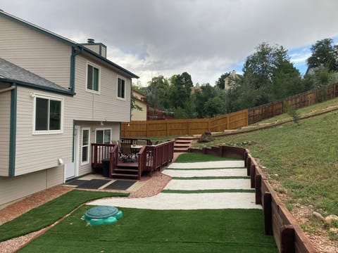 The backyard with the deck that has a propane BBQ grill and a fire pit
