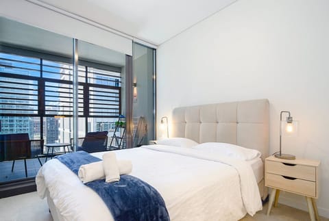 Bedroom featuring a queen-size bed, bedside tables, and balcony access.