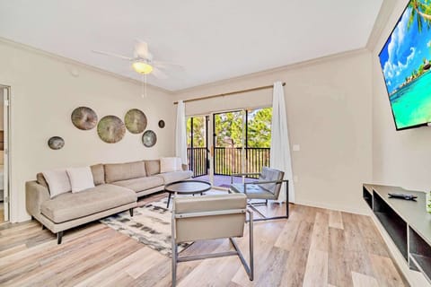 Well lighted living room with comfortable seating, a TV, and balcony access.
