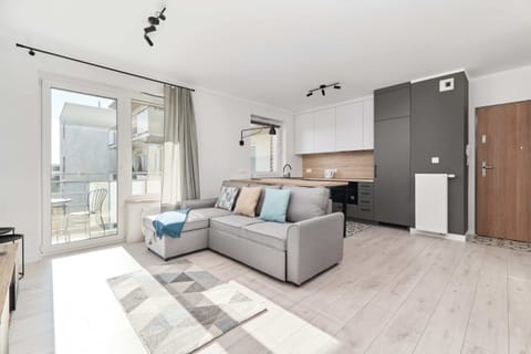 Living room with a corner sofa bed, TV, kitchenette and exit to balcony.