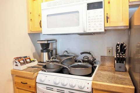 Fully equipped kitchen with brand new cookware set, knives, and coffee machine.