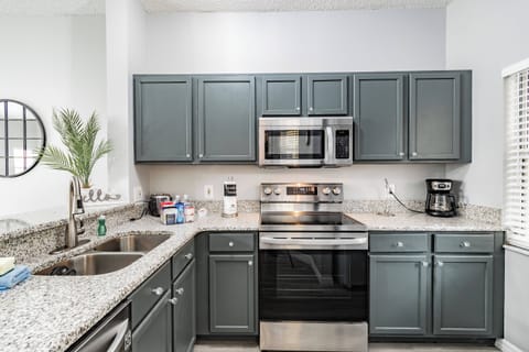 Experience the charm of this stylish kitchen featuring navy cabinetry and sleek granite countertops. With modern stainless steel appliances, including a microwave and oven, you'll enjoy a seamless and inviting cooking experience.
