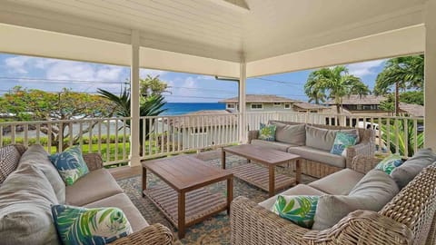 Relax on your private covered lanai with plush seating and stunning ocean views framed by swaying palms—your perfect Hawaiian retreat awaits.