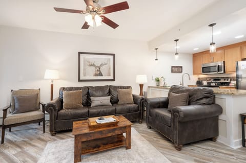 Sink into plush leather seating in your open-concept living space, where rustic charm meets modern comfort beneath soaring ceilings.