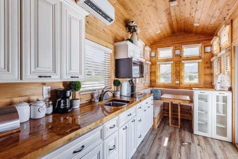 The kitchen is fully equipped with a refrigerator, freezer, microwave, cooktop, and sink with hot/cold water. Enjoy coffee from the coffee maker and ample counter space. Essentials include cookware, dishes, utensils, and plenty of storage cabinets.