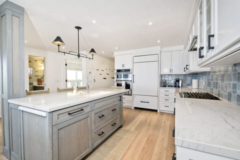 Immaculate kitchen with sub zero refrigerator, five-range gas stove, oven, microwave, and quiet Bosch dishwasher