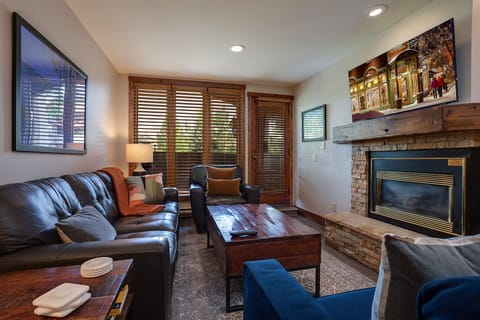 Sink into luxurious leather seating beside the stone fireplace, where warm wood tones create your perfect mountain retreat sanctuary.