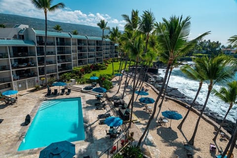 Beautiful view from your living room and lanai of the Pacific, inviting pool area and your private sandy beach :) Enjoy a stunning view of the natural saltwater pool from your lanai — a Kona favorite.