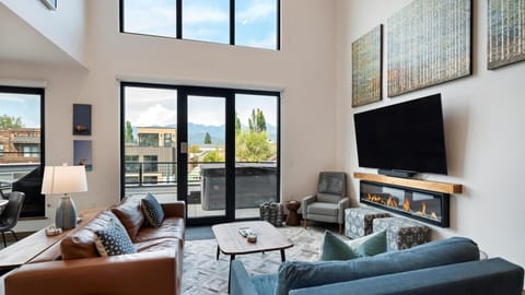 Open concept living room with gas fireplace and SmartTV, dining area, and kitchen with wrap around balcony and hot tub