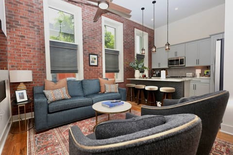 Living Room: Experience chic elegance with exposed brick, stylish seating, and gourmet kitchen access!