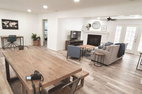 The living and dining space is designed to create an open and airy atmosphere, with the added functionality of a desk area. It also features a 65-inch smart TV for entertainment and plenty of comfortable seating options.