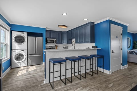 Create coastal meals in this chic navy kitchen with stainless appliances, a sleek breakfast bar, and vibrant stools—all wrapped in laid-back style and seaside charm