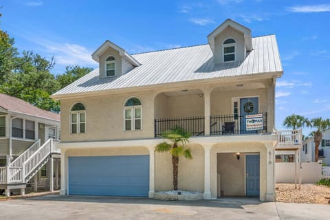 Two-story exterior with a blue door and a palm tree at Cherry Grove Reef, a 4-bedroom rental from Thomas Beach Vacations