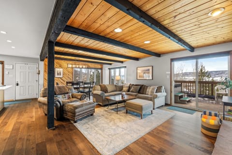Relax under stunning exposed beams in this spacious living room, where plush seating and warm wood tones create your perfect mountain retreat.
