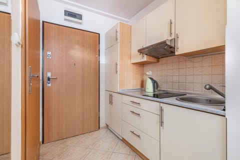 A compact, functional kitchen with light-colored cabinets and essential appliances, perfect for preparing meals in a cozy space.