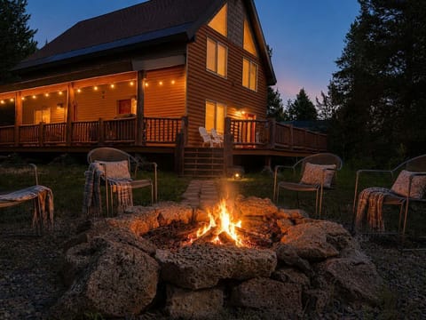 Gather under the stars around the grand stone fire pit, beautifully set against the warm, glowing backdrop of the log cabin and string-lit wrap-around deck.
