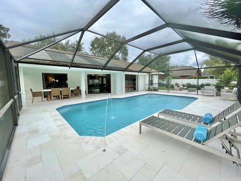 Newly remodeled heated pool w/ screened lanai, lounging areas, and dining table