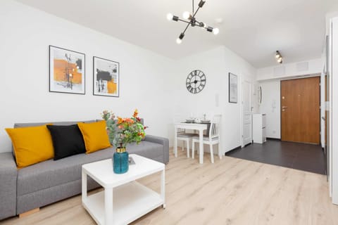 A bright living room with a comfortable sofa, vibrant cushions, and a modern dining table.
