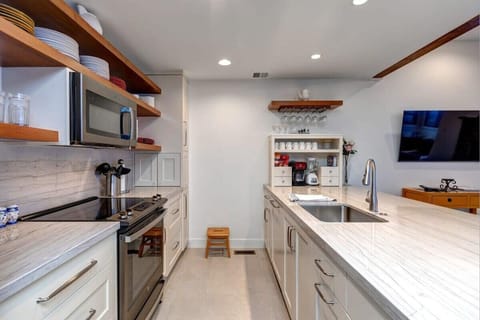 Fully-equipped kitchen with high-quality stainless steel appliances, plenty of countertop space, and breakfast bar seating