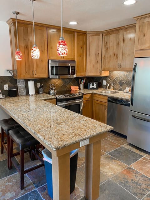 Fully-equipped kitchen with high-quality stainless steel appliances, and a breakfast bar with 6 stools