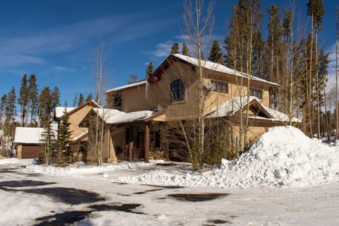 A beautiful mountain home nestled among tall aspens and evergreens, with snow-covered roofs and cleared parking areas for easy winter access.