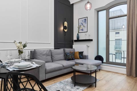 A bright living room with a cozy sofa, modern coffee table, and large windows overlooking the city.
