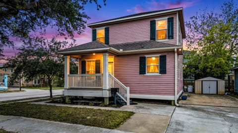 Summer Bliss glowing at golden hour — warm lights, a welcoming porch, and a Galveston corner home that looks as good at dusk as it does in the sunshine."