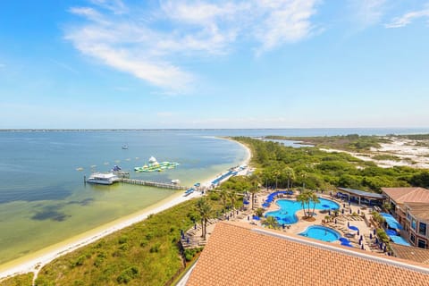 Coastal resort property nestled on a pristine waters, featuring beachfront pools, sandy shoreline access, and surrounded by natural lagoon waters and lush tropical vegetation.