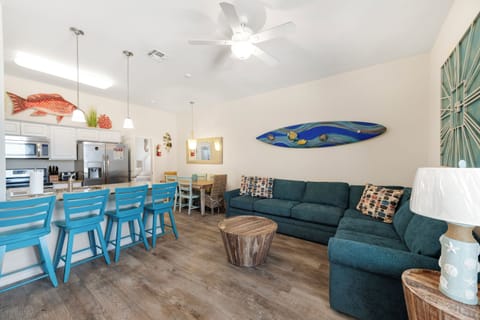 Your open-concept living space blends coastal charm with modern comfort, where ocean-themed art and soft lighting create the perfect backdrop for relaxation.