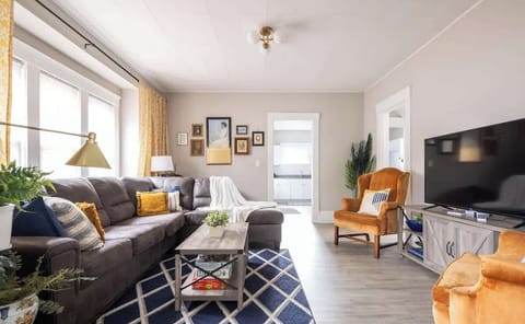 Bright living room w/ cozy seating, TV & large windows letting in natural light